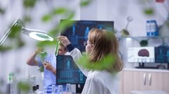 Female scientist holding and looking at a sample of liquid in a test tube. Academic scientist.