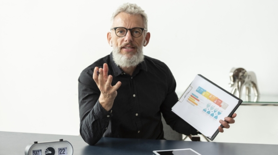 Business professional presenting AI strategy graphs on clipboard during a meeting in 2025