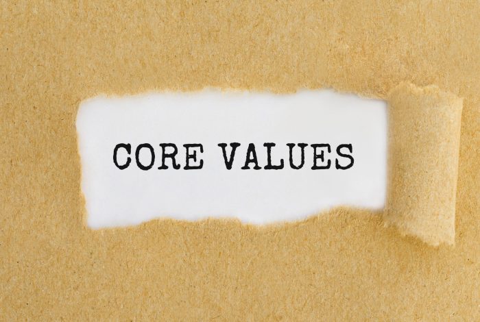 Text Core Values appearing behind ripped brown paper.